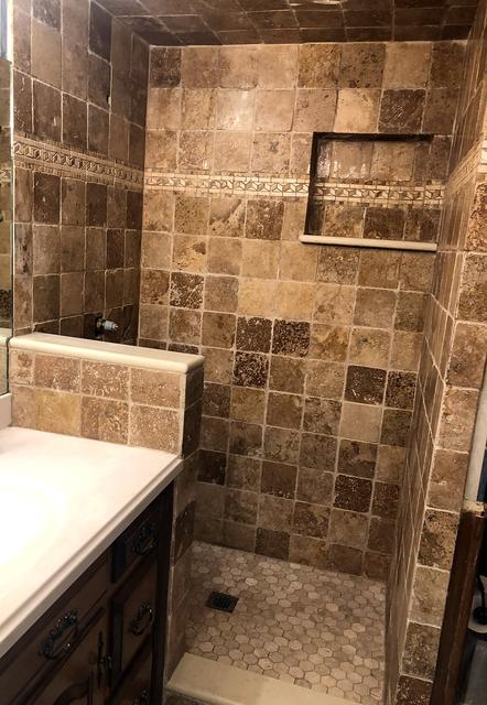 Travertine tile shower with a recessed niche